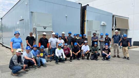 Crown employees in front of a four-section split arc-resistant switchgear enclosure